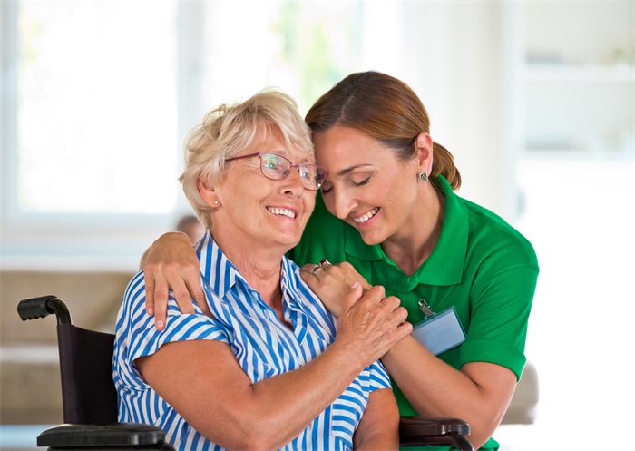 Een zorgmedewerker en een oudere vrouw lachen samen